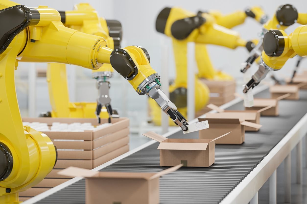 Industrial robotic arms performing automated box packing on a conveyor system in a high-speed packaging automation environment.