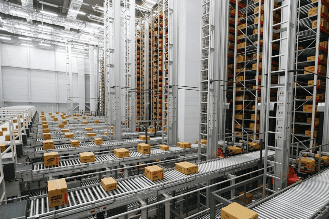 Automated storage and retrieval system (ASRS) with multiple conveyor lines transporting cartons through a high-density warehouse, demonstrating high-throughput order processing and material flow during peak operations