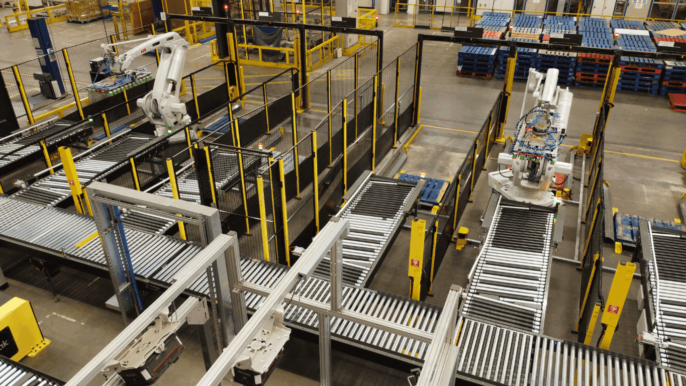 Industrial end-of-line automation system featuring robotic palletisers integrated with motorised roller conveyors for automated packaging and dispatch operations.