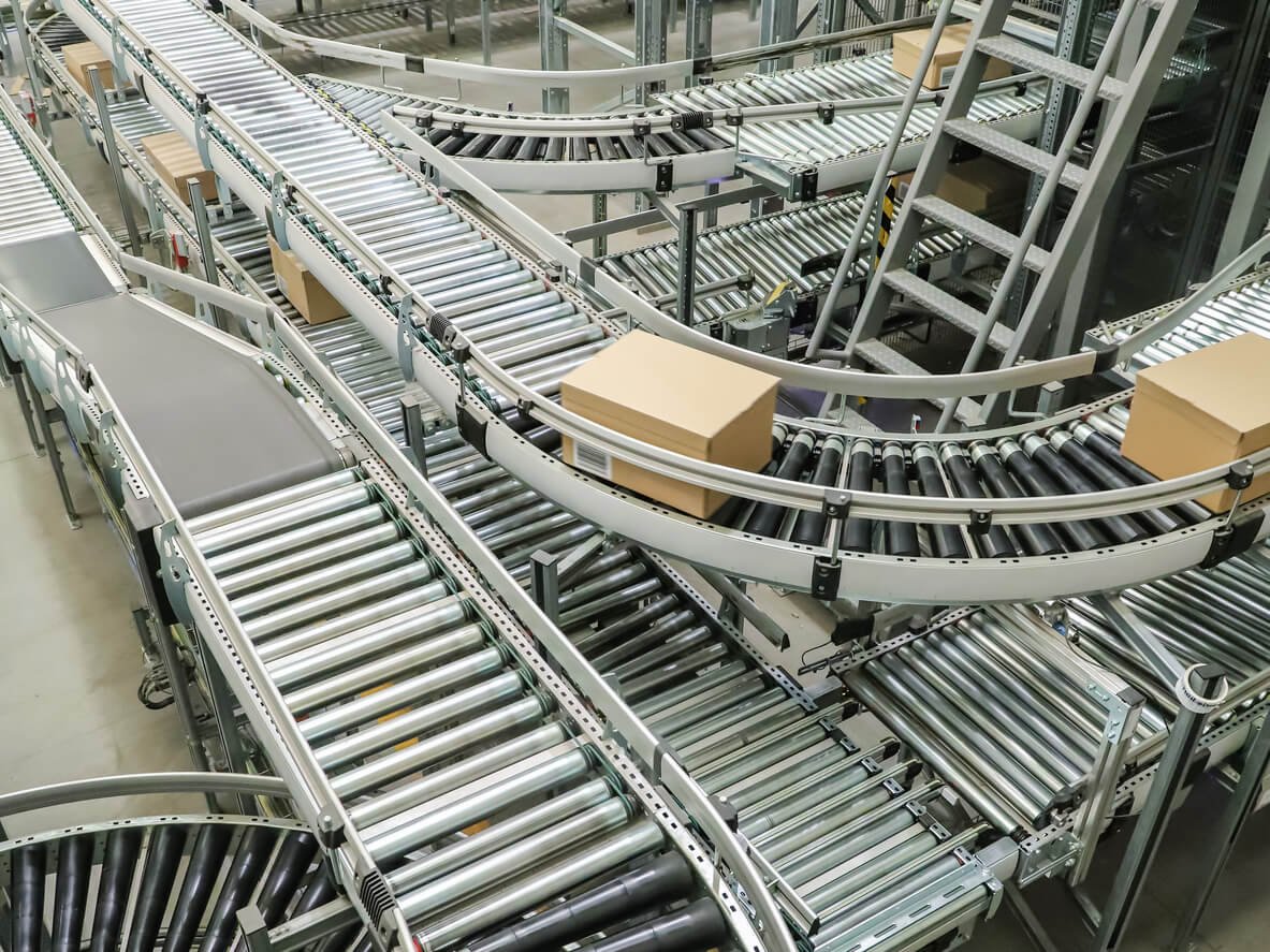 Multi-level roller conveyor system transporting cartons through an automated warehouse packaging and sortation network