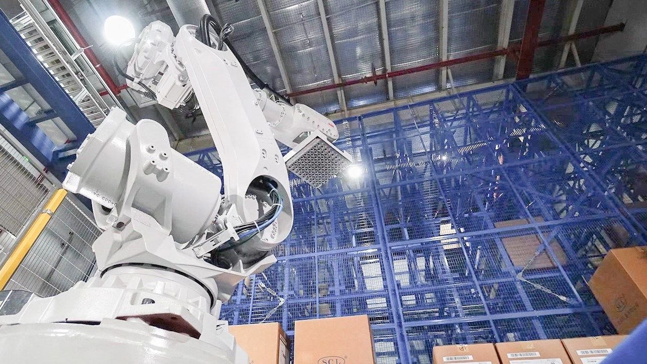 Industrial robotic arm operating within automated warehouse racking system for robotic process automation in logistics
